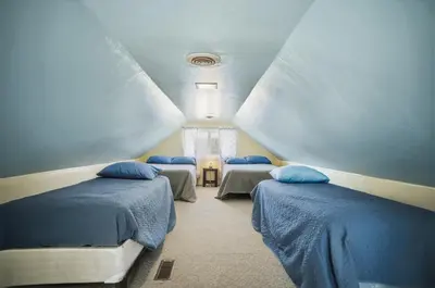 a attic room with three beds and a window at Angler's Cottage with Boat Parking by Lake Erie in Port Clinton