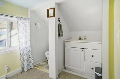 a white bathroom with a toilet and a sink at Angler's Cottage with Boat Parking by Lake Erie in Port Clinton