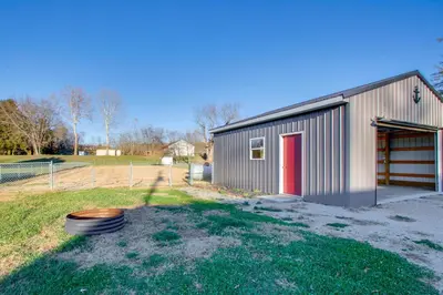a metal building with a red door and a yard at Fully Updated! Zanesville Home with River Views in Zanesville