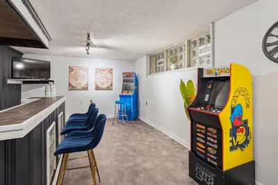 a kitchen with a video game arcade and two blue stools at Steps to Edgewater - Sleeps 14 - Fun Game Room Retreat in Cleveland