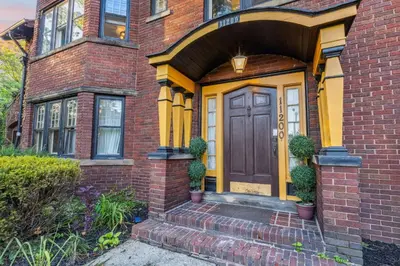 a brick house with a yellow front door at Steps to Edgewater - Sleeps 14 - Fun Game Room Retreat in Cleveland