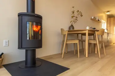 a wood burning stove in a living room with a table at The Ffern in Logan