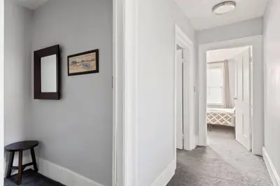 a hallway with white walls and a stool and a mirror at W38 Front in Cleveland