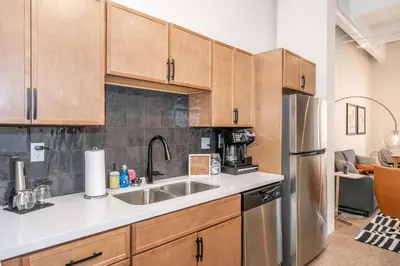 a kitchen with wooden cabinets and a stainless steel refrigerator at The 333 Suites - For 24 Guests in Cincinnati