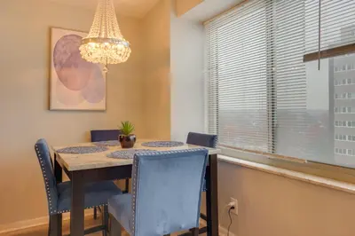 a dining room with a table and chairs and a chandelier at Cozy 12th-Floor Studio with Lake Erie Views! in Lakewood