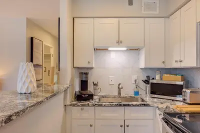 a kitchen with white cabinets and a sink at Cozy 12th-Floor Studio with Lake Erie Views! in Lakewood