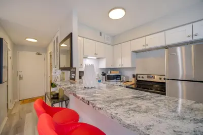 a kitchen with a counter and red chairs in it at Cozy 12th-Floor Studio with Lake Erie Views! in Lakewood