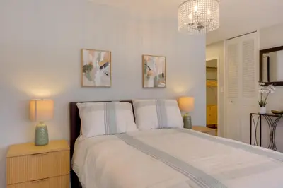 a bedroom with a bed with two lamps and a chandelier at Cozy 12th-Floor Studio with Lake Erie Views! in Lakewood