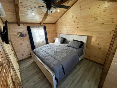 a bed in a log cabin with a ceiling fan at Wayne Cabin