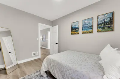 a white bedroom with a bed and three paintings on the wall at Family-owned 3BR in Larchmere Near Hospitals with Parking in Cleveland