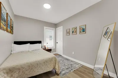 a white bedroom with a bed and a mirror at Family-owned 3BR in Larchmere Near Hospitals with Parking in Cleveland