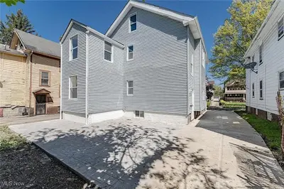 a gray house with a driveway next to a building at Family-owned 3BR in Larchmere Near Hospitals with Parking in Cleveland