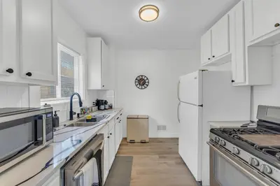 a white kitchen with white cabinets and a refrigerator at Family-owned 3BR in Larchmere Near Hospitals with Parking in Cleveland