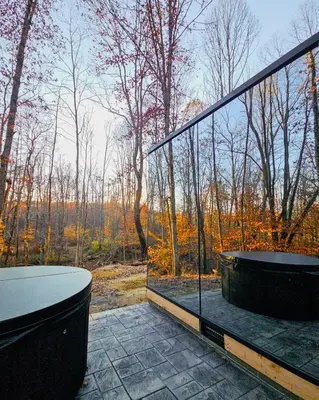 a balcony with a tub and a view of the woods at The Mirage Escape in New Plymouth