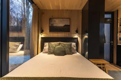 a bedroom with a bed and a large window at The Illusion Hideaway in New Plymouth