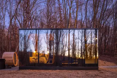 a glass house in the middle of a forest at The Illusion Hideaway in New Plymouth