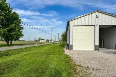 a white garage with a large door next to a road at Patio and Parking! Modern Bunkhouse Near Lake Erie in Oak Harbor