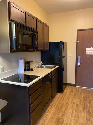 a kitchen with a sink and a black refrigerator at Suburban Studios Washington, PA in Washington