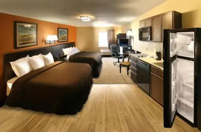 a hotel room with two beds and a kitchen at Suburban Studios Washington, PA in Washington