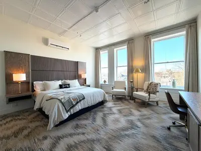 a bedroom with a bed and a desk and windows at Hotel Thoroughbred in Paris