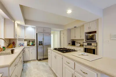 a large white kitchen with white cabinets and appliances at 7 Mi to Dtwn Toledo Spacious Family Home! in Perrysburg
