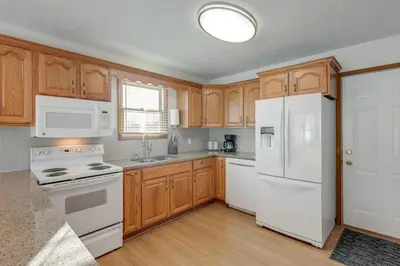 a kitchen with white appliances and wooden cabinets at 1 mile to Downtown! Boat, Hike and Fish in Liberty