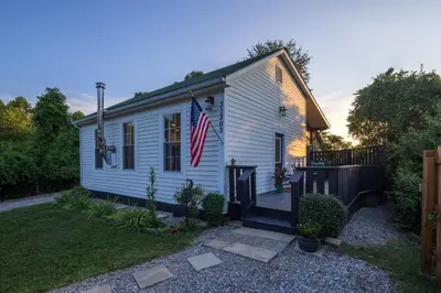 a white house with an american flag on it at Cozy Spring Night HotTub Firepit PetFriendly Patio in McArthur