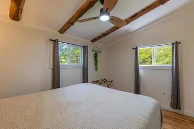 a bedroom with a white bed and two windows at Lakefront Vibes Lake Access•Hot Tub•Firepit•Pets in Rockbridge