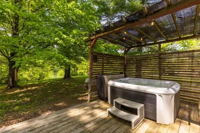 a bath tub sitting under a pergola on a wooden deck at Lakefront Vibes Lake Access•Hot Tub•Firepit•Pets in Rockbridge