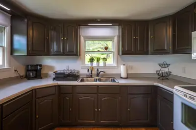 a kitchen with brown cabinets and a sink at Nature-Quiet Retreat • Firepit BBQ • PetFriendly in McArthur