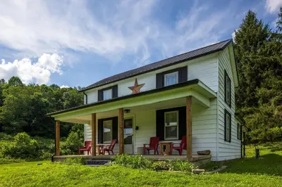 a small house with red chairs on the porch at Nature-Quiet Retreat • Firepit BBQ • PetFriendly in McArthur