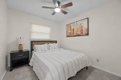 a white bedroom with a bed and a ceiling fan at Home to Unwind in Columbus