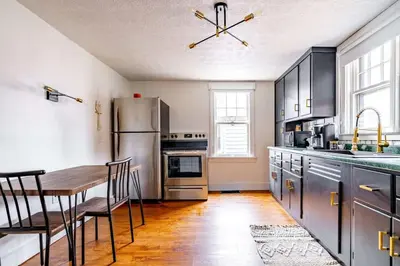 a kitchen with a table and a stainless steel refrigerator at Yoctangee House by Jungle House in Chillicothe