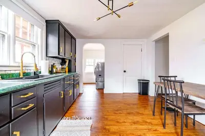 a kitchen with black cabinets and a wooden floor at Yoctangee House by Jungle House in Chillicothe