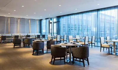 a restaurant with tables and chairs and large windows at AC Hotel Cincinnati at Liberty Center in West Chester