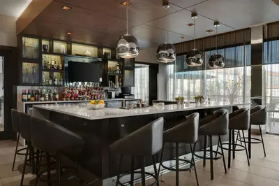 a bar with stools in a room with windows at AC Hotel Cincinnati at Liberty Center in West Chester