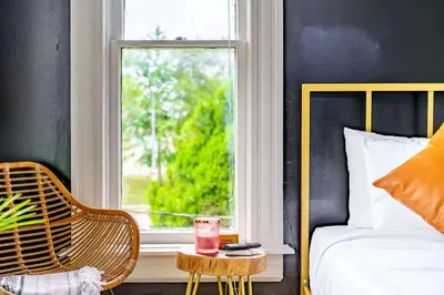 a bedroom with a bed and a window with a drink on a table at Jungle Fever by Jungle House Walk to High Street Near Convention Center OSU & Nationwide Arena Downtown & Short North 5 800 Reviews Private Parking in Columbus