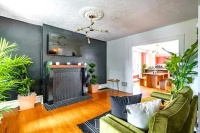 a living room with a fireplace and green furniture at Bamboo Bungalow by Jungle House Near Convention Center OSU & Nationwide Arena Walk to High Street Downtown & Short North 5 800 Reviews Private Parking in Columbus