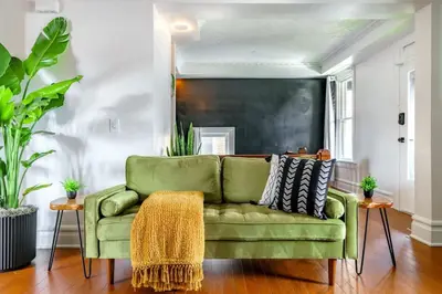 a green couch in a living room with plants at Bamboo Bungalow by Jungle House Near Convention Center OSU & Nationwide Arena Walk to High Street Downtown & Short North 5 800 Reviews Private Parking in Columbus