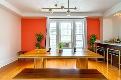 a dining room with orange walls and a wooden table at Bamboo Bungalow by Jungle House Near Convention Center OSU & Nationwide Arena Walk to High Street Downtown & Short North 5 800 Reviews Private Parking in Columbus