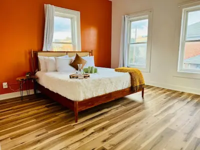a bedroom with a bed with orange walls and wooden floors at Cozy Casita by Jungle House Downtown & Short North Free Parking 5 800 Reviews Near Convention Center & Nationwide Arena & Ohio State Walk to High Street in Columbus