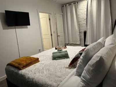 a bedroom with a white bed with a television on the wall at Jungle Vibe by Jungle House Downtown & Short North Free Parking 5 800 Reviews Near Convention Center & Nationwide Arena & Ohio State Walk to High Street in Columbus