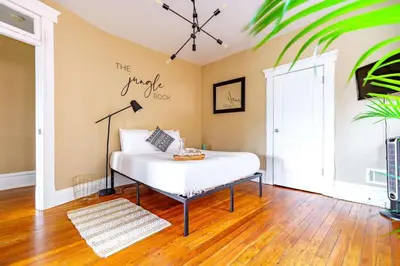 a bedroom with a white bed with a table at Jungle Book by Jungle House Walkable to High Street Downtown & Short North Near Nationwide Arena OSU & Convention Center Free Parking 5 800 Reviews in Columbus