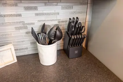 a container filled with utensils next to a wall at Black Tie Affair - Eloquent Riverfront Experience in New Richmond