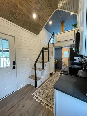 a living room with a staircase in a house at Stargazers' Retreat A Tiny Home on the Riverside in New Richmond