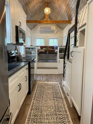 a kitchen with white cabinets and a rug at Stargazers' Retreat A Tiny Home on the Riverside in New Richmond