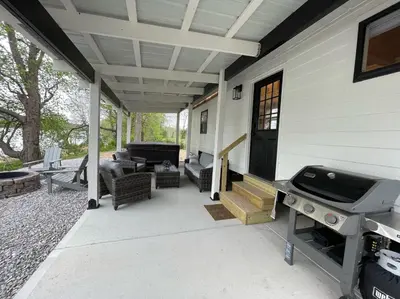 a screened in porch with a grill and a patio at Stargazers' Retreat A Tiny Home on the Riverside in New Richmond