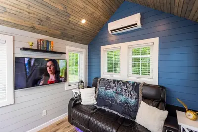 a living room with a black leather couch and a tv at Hagrid's Hut - Harry Potter Riverfront Experience in New Richmond
