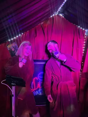 a man and a woman sitting in a room with microphones at GENIE ROMANCE SUITE with King Size Flying Carpet Bed, Jet Tub, Karaoke, Sultan's Foot Massage Room in Mount Vernon