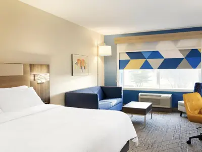 a hotel room with a bed and a blue couch at Holiday Inn Express & Suites Mentor - Banquet Center by IHG in Mentor